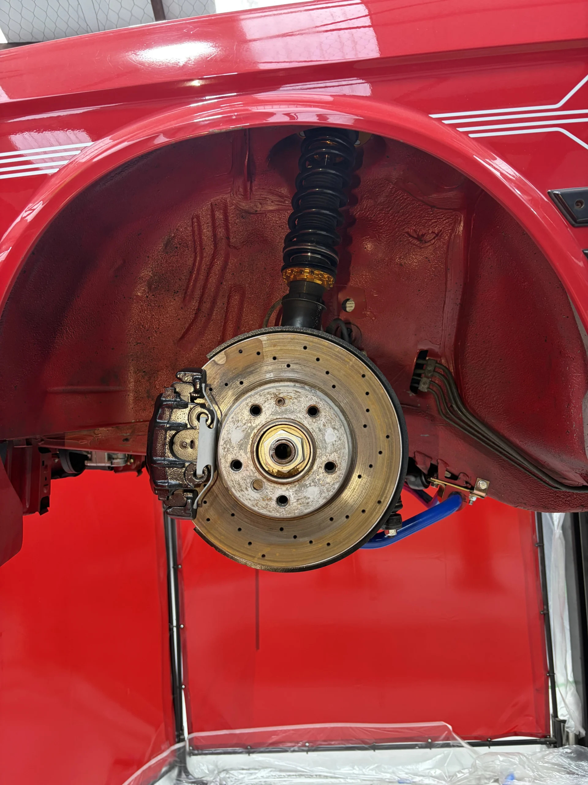 BMW E28 front wheel arch, hub and drilled disc after dry ice blasting, clean and dry with factory finishes intact