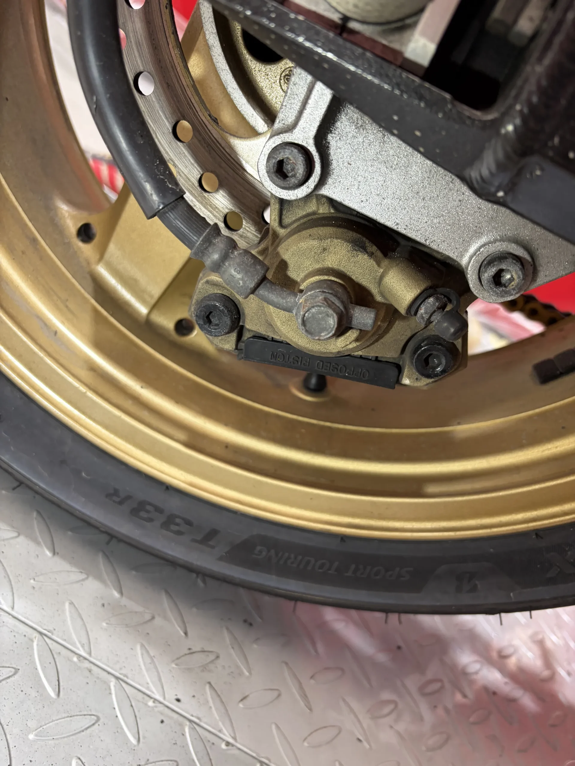 2004 Kawasaki ZX-12R front wheel, caliper and disc before dry ice cleaning, under road film and chain fling