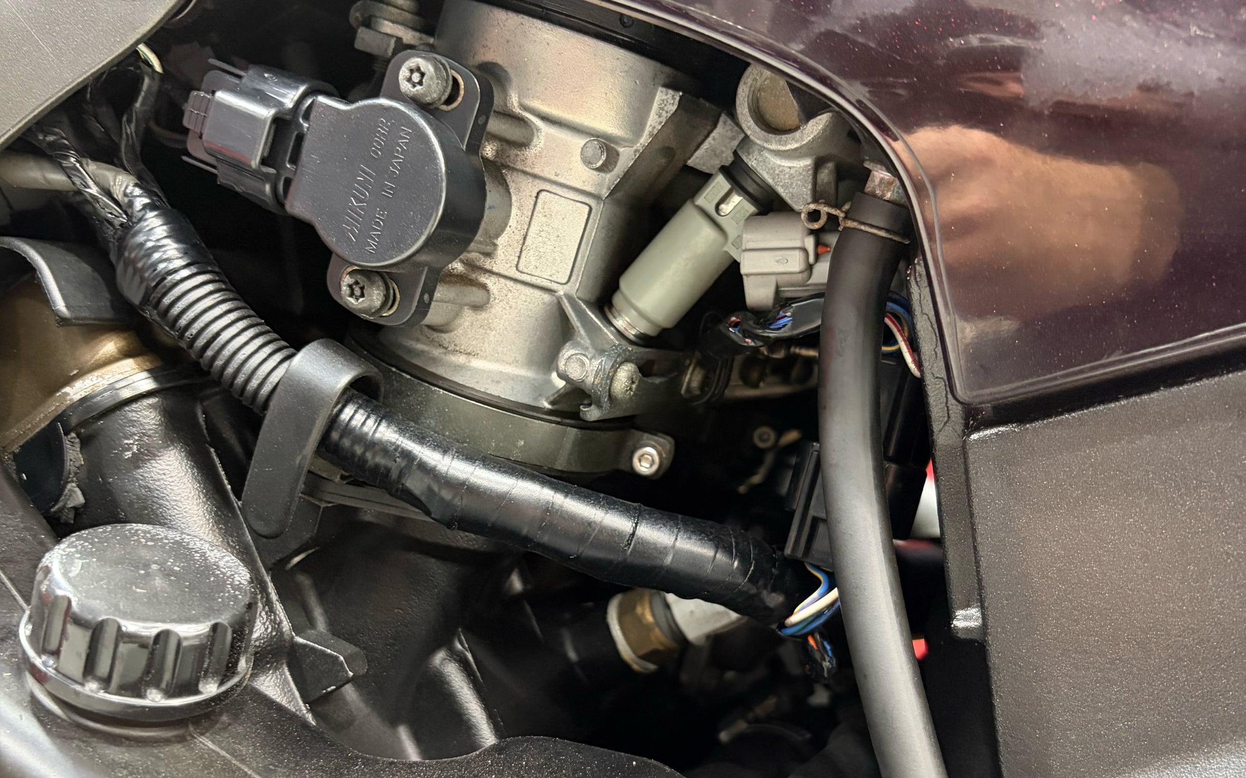 Close-up of a clean throttle body, wiring and hoses in an engine bay