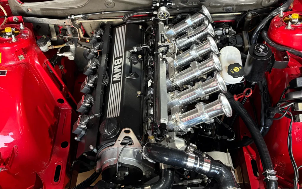 BMW E28 engine bay with individual throttle bodies after dry ice cleaning